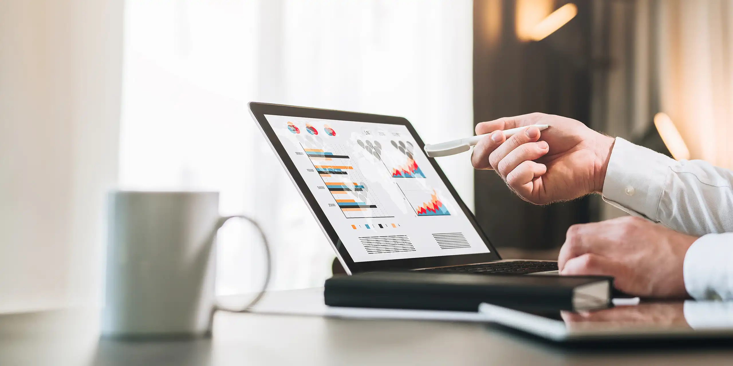 Hand pointing at an analytics dashboard on a laptop showing charts and performance data