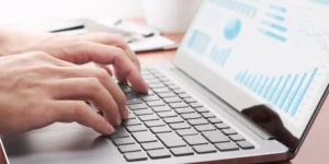 Hands typing on a laptop with analytics charts—ecommerce performance tracking and optimization.